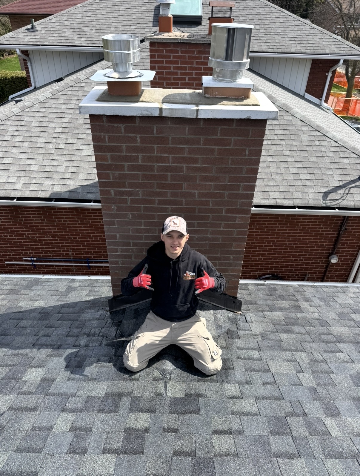 Nick Masonry mason on a rooftop next to a rebuilt brick chimney